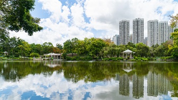 The calm waters in the Artificial Lake mirrors the natural landscape and the built environment under the vast blue sky.